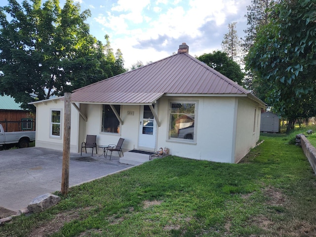 213 Washington St, Thompson Falls, MT 59873 - back of property featuring a chimney, stucco siding, a yard, and metal roof