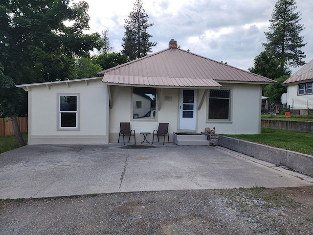 213 Washington St, Thompson Falls, MT 59873 - rear view of house with a chimney, fence, stucco siding, a porch, and metal roof