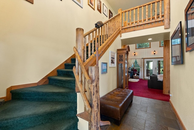 staircase featuring french doors and a towering ceiling