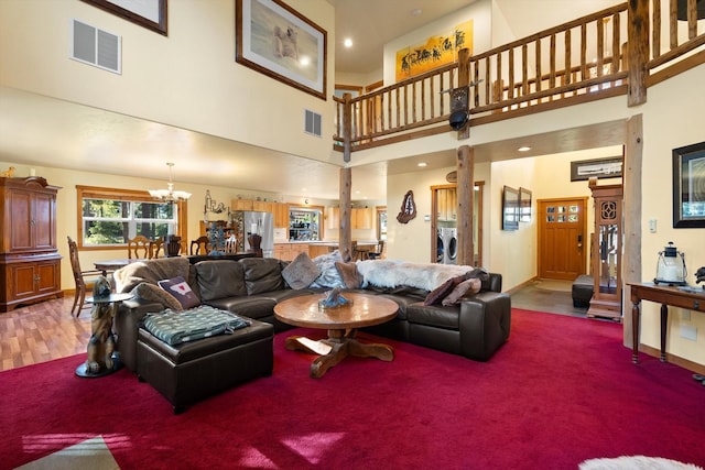 living room featuring washing machine and dryer, a chandelier, a high ceiling, and hardwood / wood-style flooring