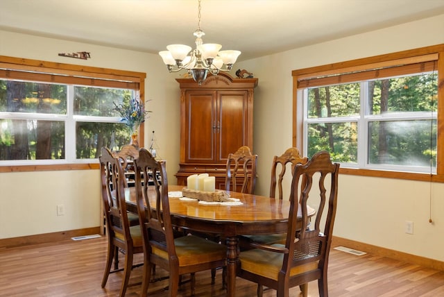 dining room featuring light wood-type flooring and an inviting chandelier