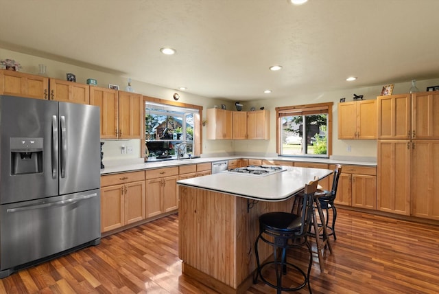 kitchen with appliances with stainless steel finishes, light wood-type flooring, a kitchen island, and plenty of natural light