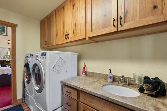 laundry room with cabinets, washing machine and dryer, sink, and hardwood / wood-style flooring