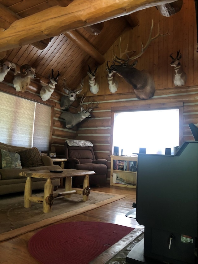 living room featuring log walls, hardwood / wood-style flooring, high vaulted ceiling, and beam ceiling