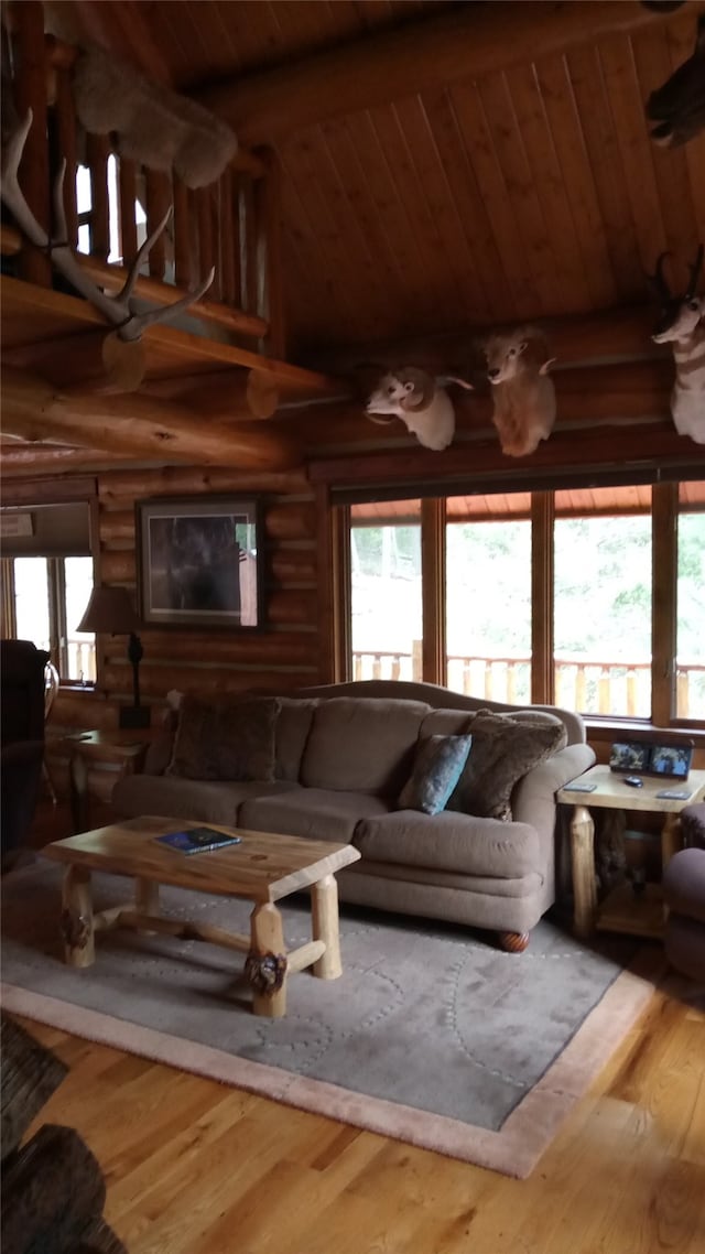 living room with lofted ceiling with beams, log walls, wooden ceiling, and wood-type flooring