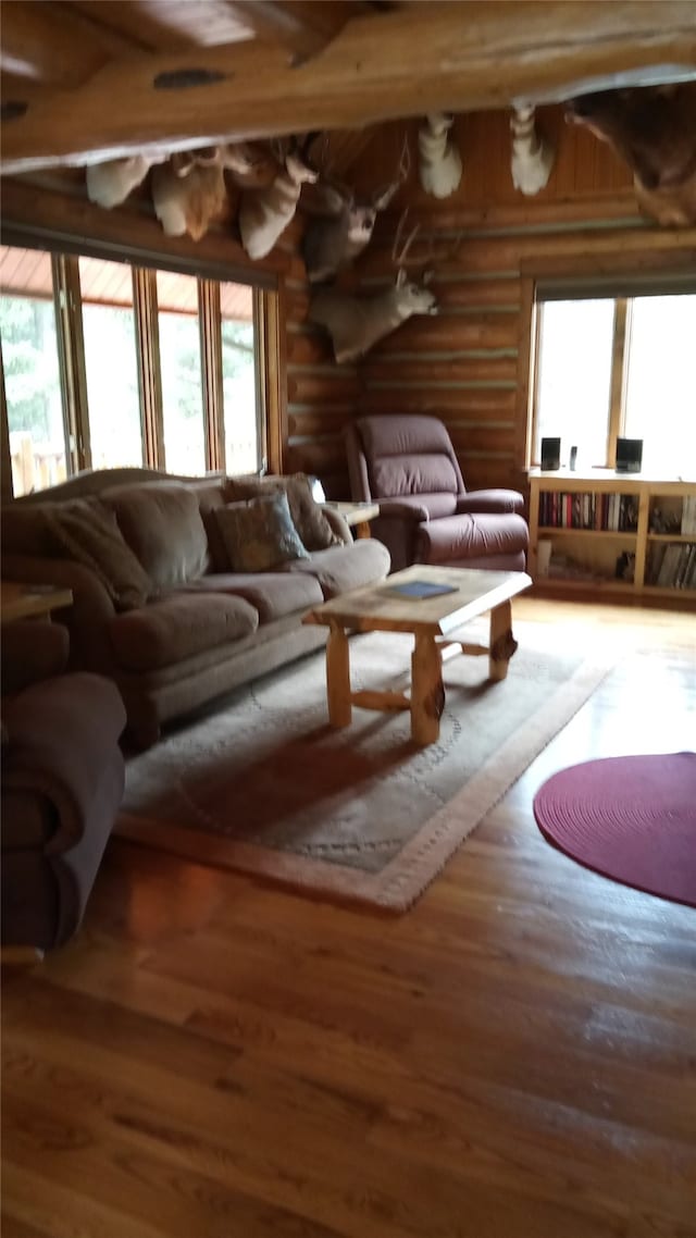 living room with log walls, hardwood / wood-style flooring, and beam ceiling