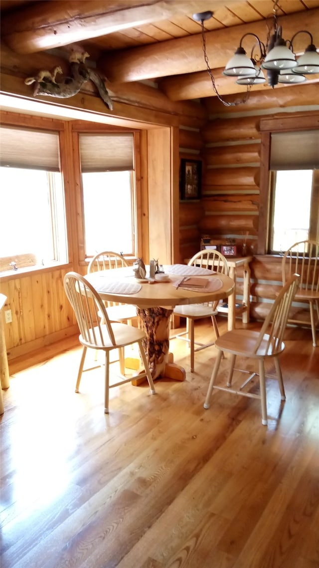 unfurnished dining area featuring beamed ceiling, light wood-type flooring, and rustic walls