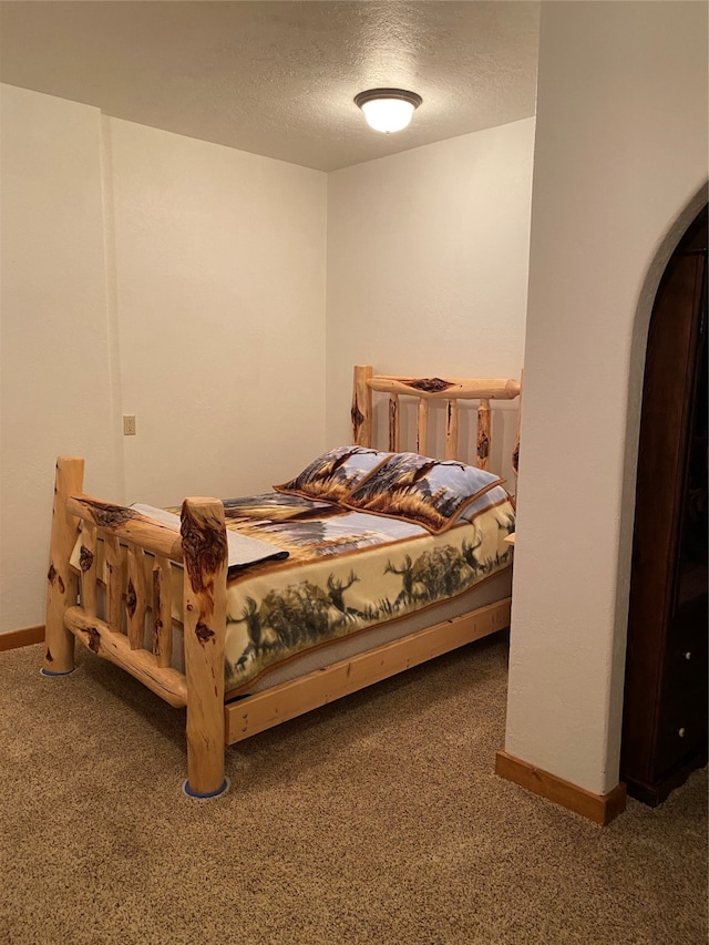 bedroom featuring dark carpet and a textured ceiling