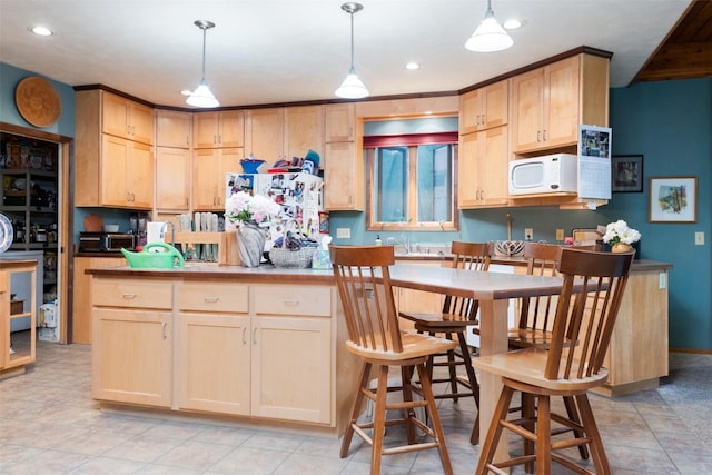 kitchen featuring sink, light brown cabinets, refrigerator, and decorative light fixtures