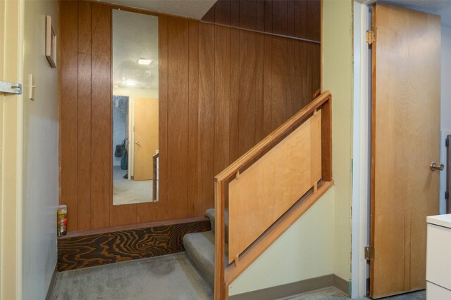 staircase with carpet flooring and wood walls