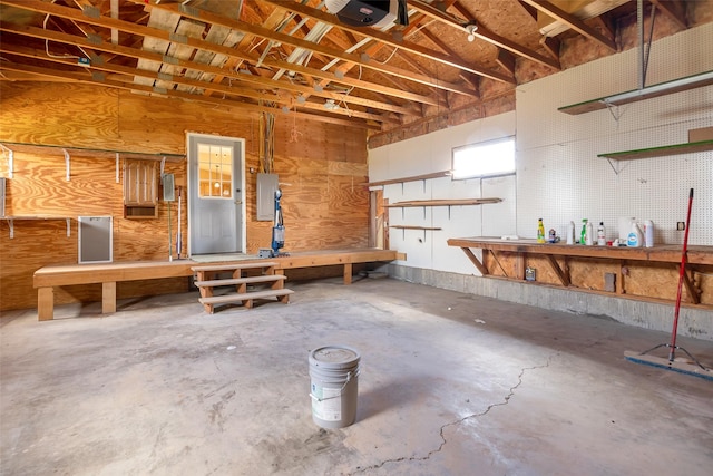 garage featuring a workshop area, electric panel, and a garage door opener