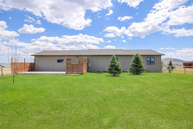 rear view of house featuring a mountain view and a yard