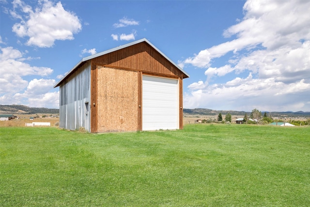 view of outbuilding featuring a lawn, a mountain view, and a garage