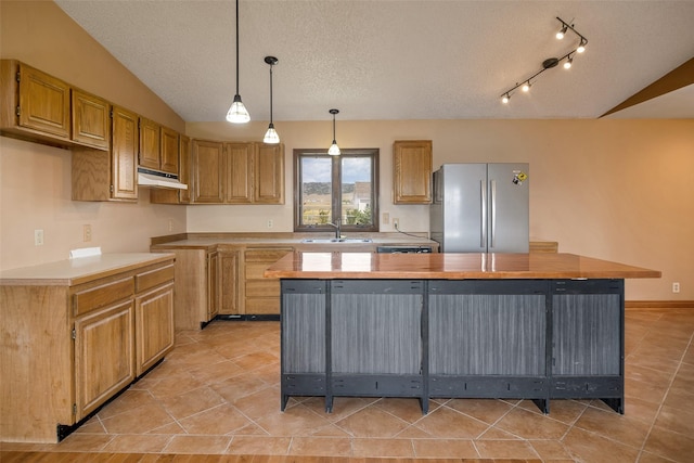 kitchen with stainless steel refrigerator, a center island, lofted ceiling, and sink