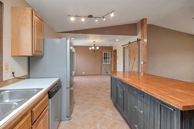 kitchen with dishwasher, a barn door, butcher block countertops, lofted ceiling, and decorative light fixtures