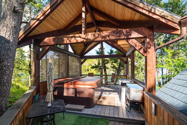 wooden deck with a hot tub and a gazebo