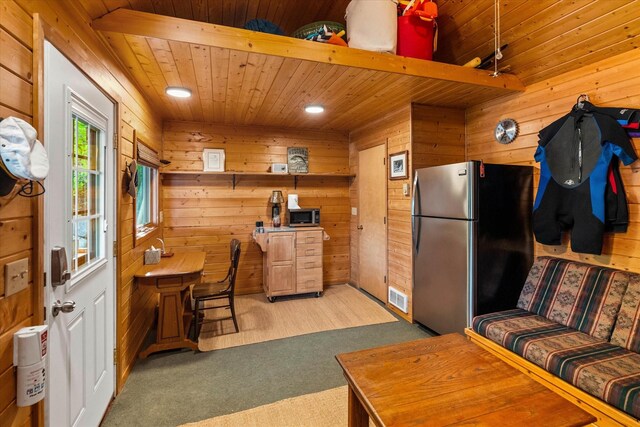 carpeted living room with wood ceiling and wood walls