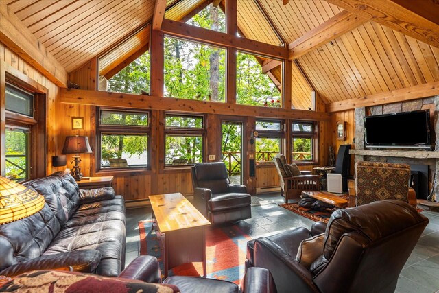 living room featuring high vaulted ceiling, wooden walls, and a stone fireplace