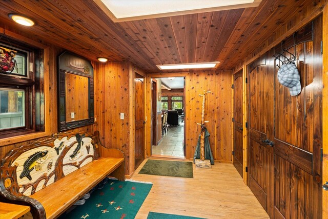 hallway featuring wooden ceiling, wooden walls, and light hardwood / wood-style floors