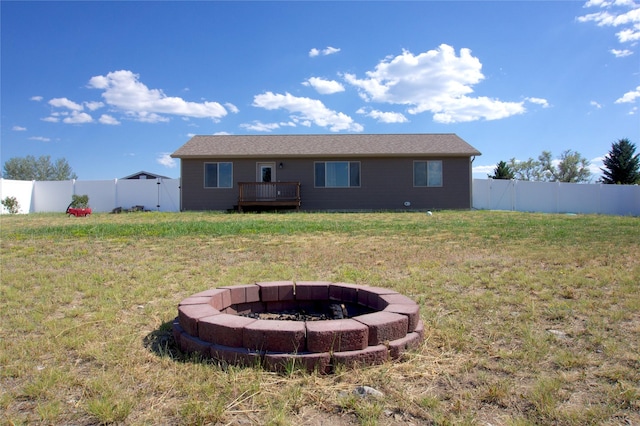 back of property with a fire pit, a deck, and a yard