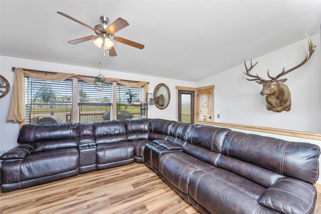 living room with light hardwood / wood-style flooring, vaulted ceiling, and ceiling fan