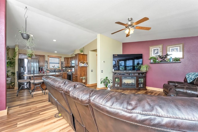 living room with recessed lighting, a ceiling fan, baseboards, vaulted ceiling, and light wood-type flooring