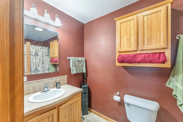 bathroom with decorative backsplash, vanity, and toilet