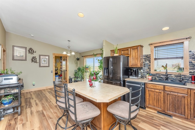 kitchen featuring pendant lighting, sink, backsplash, stainless steel refrigerator with ice dispenser, and black dishwasher