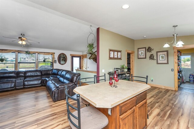 kitchen featuring ceiling fan, decorative light fixtures, light wood-type flooring, and a center island