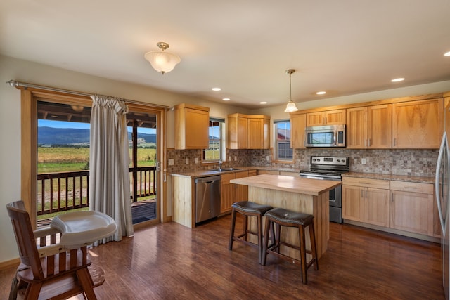 kitchen with stainless steel appliances, dark wood-type flooring, a center island, butcher block countertops, and hanging light fixtures