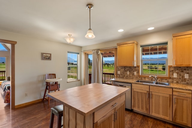 kitchen featuring pendant lighting, a center island, backsplash, sink, and stainless steel dishwasher