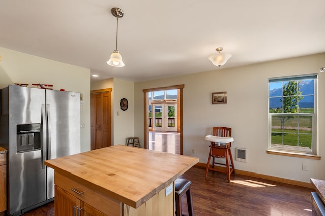 kitchen featuring butcher block counters, stainless steel fridge with ice dispenser, dark hardwood / wood-style floors, decorative light fixtures, and a kitchen island