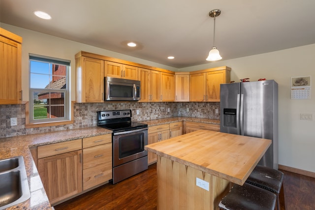 kitchen featuring decorative backsplash, appliances with stainless steel finishes, dark hardwood / wood-style flooring, a center island, and hanging light fixtures