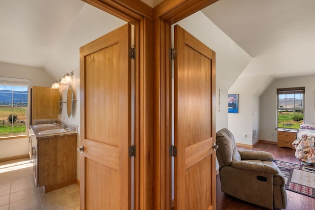 corridor with sink, light tile patterned floors, and vaulted ceiling