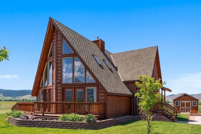 rear view of house featuring a lawn and a storage unit