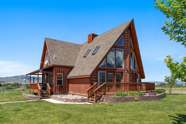 rear view of property featuring a yard and a deck with mountain view