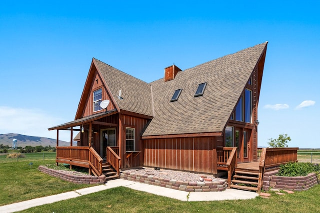 back of house with a mountain view, a yard, and covered porch