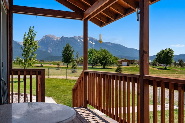 wooden deck featuring a mountain view and a yard