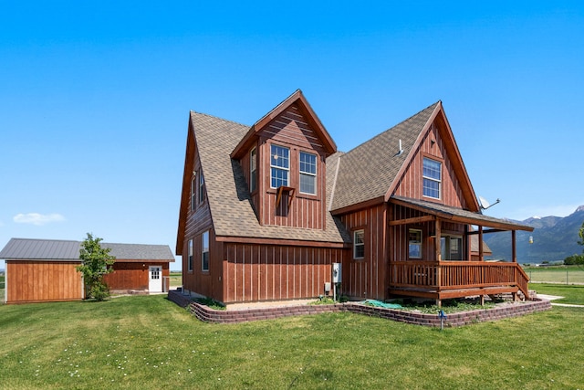 rear view of house with a mountain view and a lawn