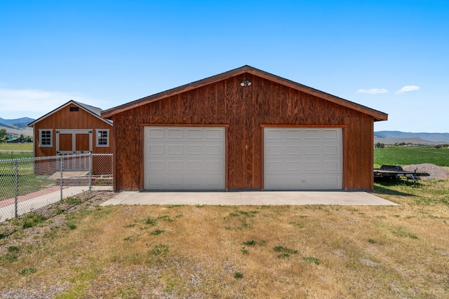 exterior space featuring an outbuilding, a mountain view, a garage, and a front lawn