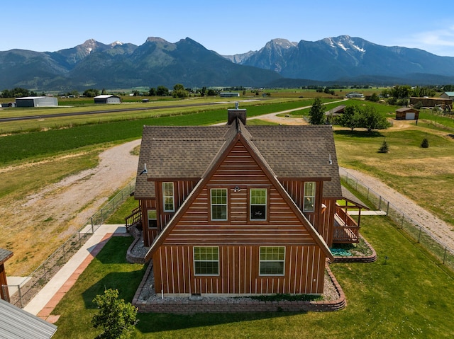 rear view of property with a lawn, a mountain view, and a rural view