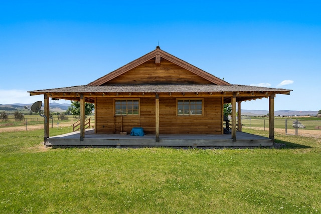 rear view of house with a mountain view, a rural view, and a yard