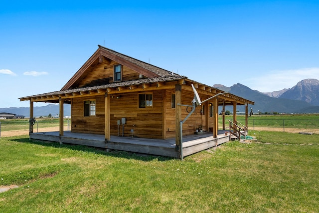 rear view of house with a mountain view, a rural view, and a lawn