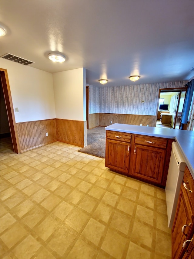 kitchen with wooden walls, white dishwasher, and kitchen peninsula