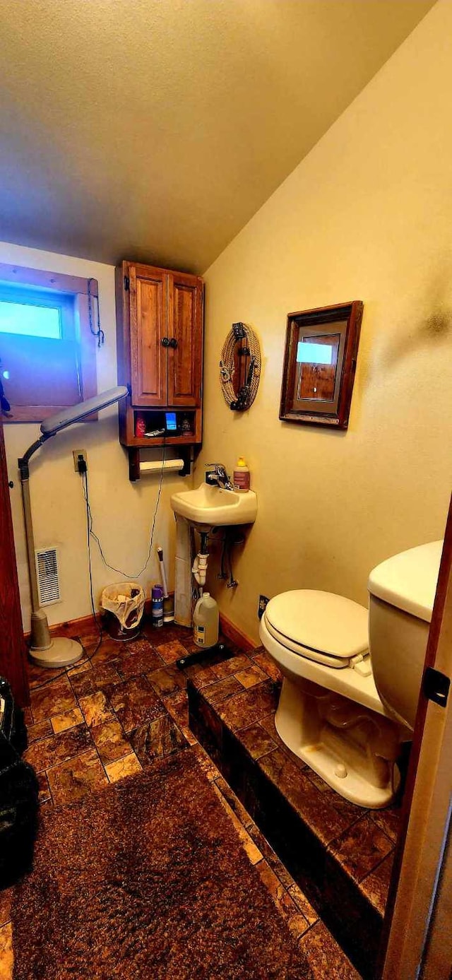 bathroom with toilet, vaulted ceiling, and a textured ceiling