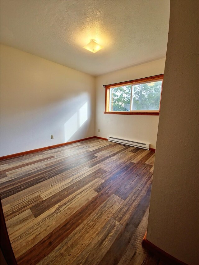 512 S Oak St, Townsend, MT 59644 - spare room with a baseboard radiator, baseboards, wood finished floors, and a textured ceiling