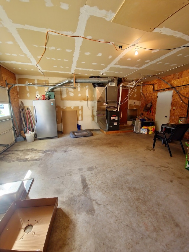 basement featuring heating unit and stainless steel refrigerator