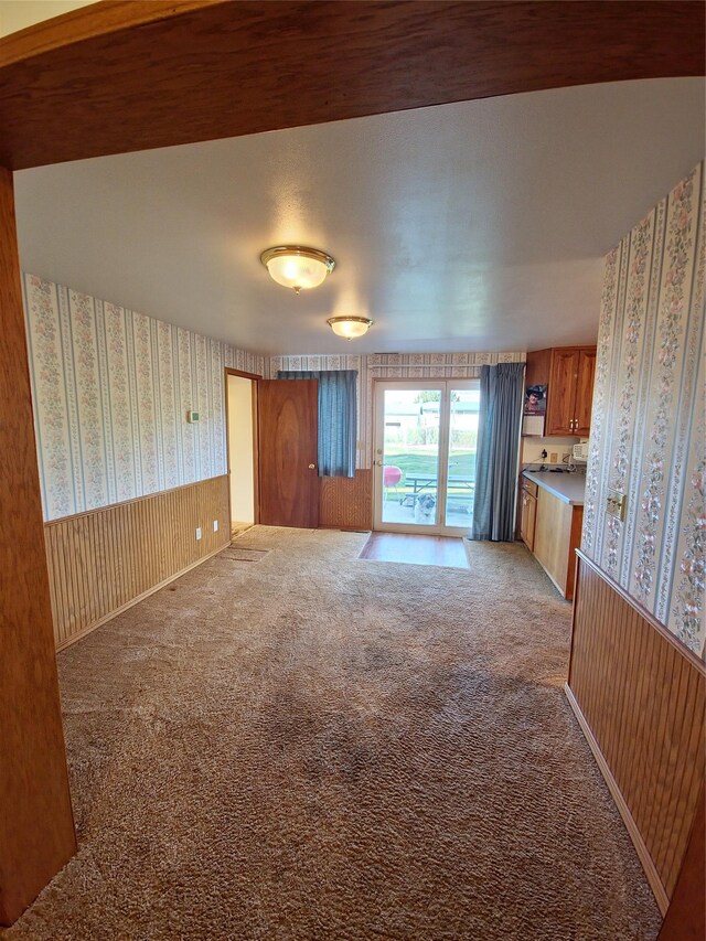 512 S Oak St, Townsend, MT 59644 - unfurnished living room with wallpapered walls, a wainscoted wall, and light carpet