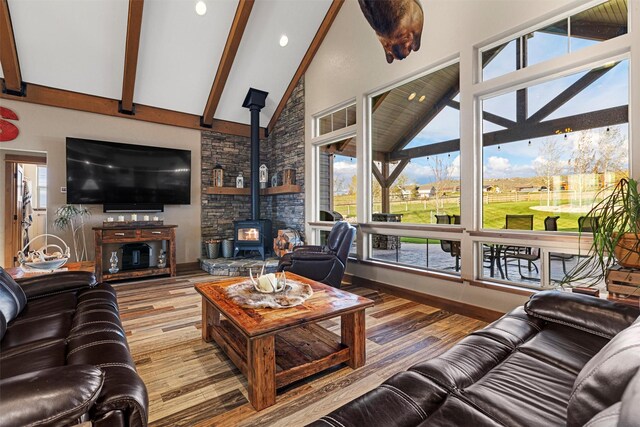 living room with beam ceiling, a wood stove, hardwood / wood-style flooring, and high vaulted ceiling