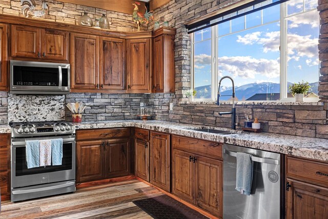 kitchen featuring decorative backsplash, a mountain view, sink, light hardwood / wood-style floors, and appliances with stainless steel finishes